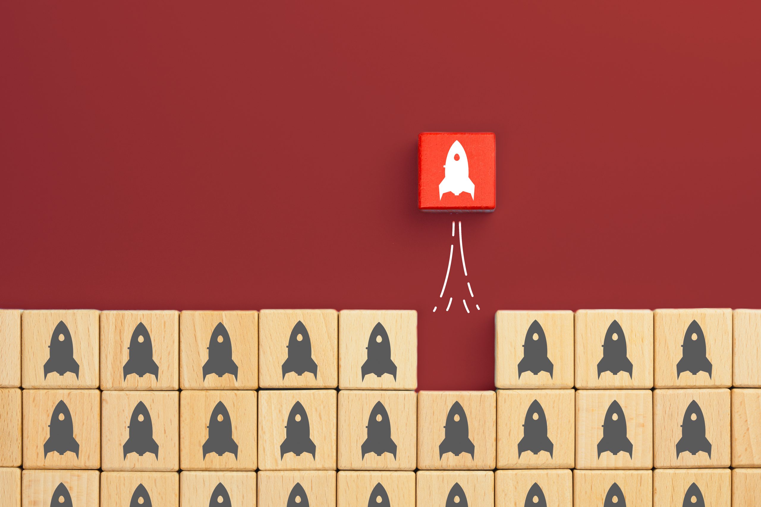 Red wooden block stand out from the crowd with rocket launch icons. Business start up, Leadership, Development and Innovation concept